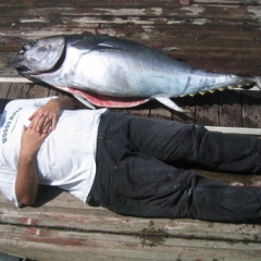 Glenn is lying on the boat next to a large fish